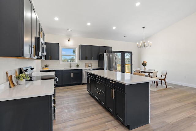 kitchen featuring a sink, light countertops, appliances with stainless steel finishes, dark cabinets, and a chandelier