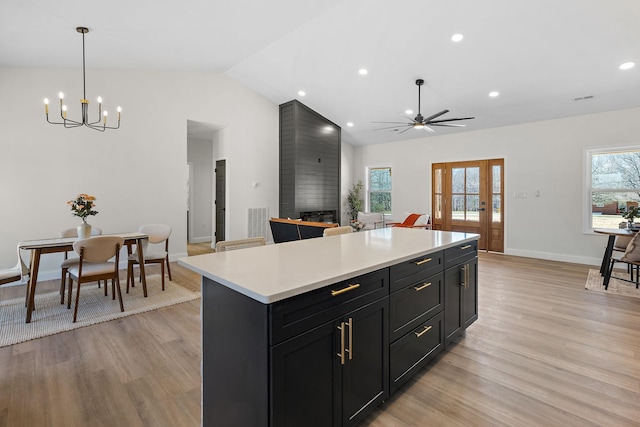 kitchen featuring a wealth of natural light, a kitchen island, dark cabinets, and light countertops