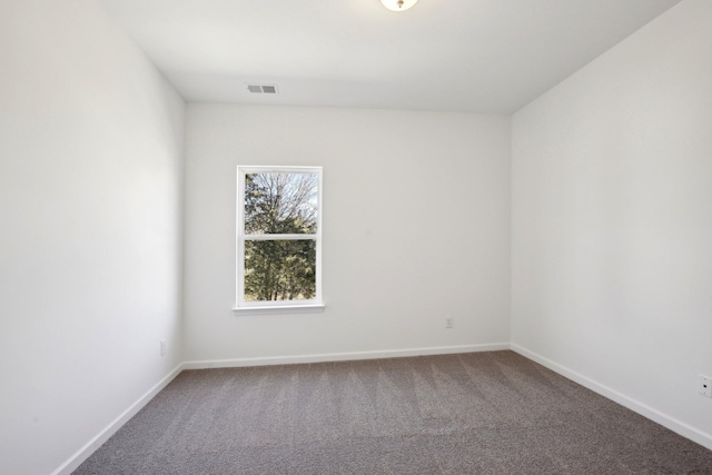 spare room with carpet floors, visible vents, and baseboards