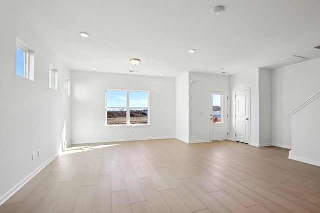 unfurnished living room with a wealth of natural light, wood finished floors, and baseboards