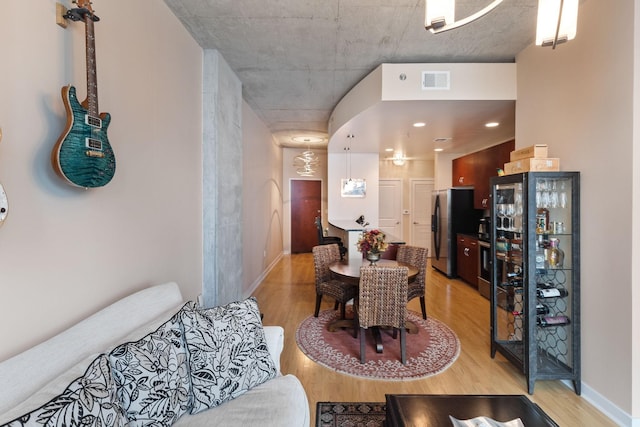 dining room featuring arched walkways, visible vents, light wood-style flooring, and baseboards