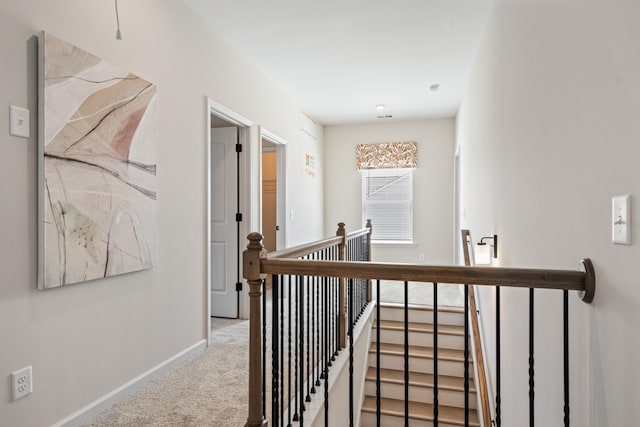 corridor featuring an upstairs landing, baseboards, and carpet floors