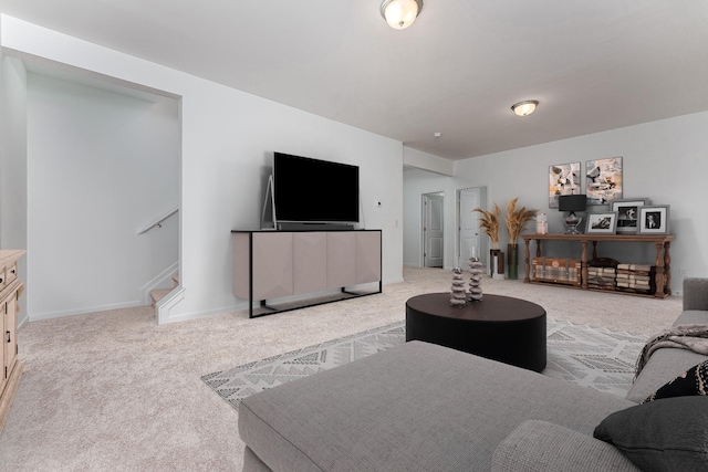 carpeted living room with stairs and baseboards