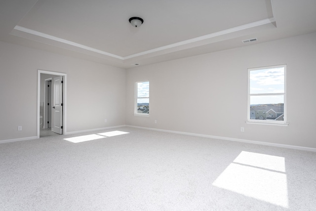 spare room with a tray ceiling, carpet floors, baseboards, and visible vents