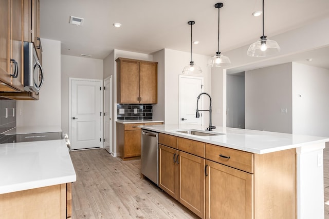 kitchen featuring visible vents, light wood-style flooring, stainless steel appliances, a sink, and tasteful backsplash