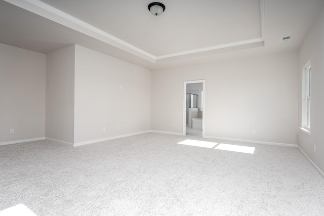unfurnished room with visible vents, light colored carpet, a raised ceiling, and baseboards