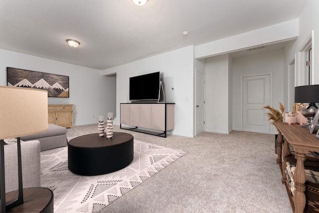 living area featuring visible vents, light carpet, and baseboards