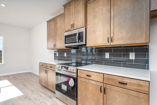 kitchen with light countertops, light wood-style flooring, tasteful backsplash, and stainless steel appliances