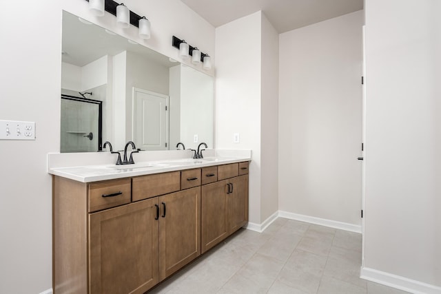 bathroom featuring a sink, baseboards, a shower with door, and double vanity