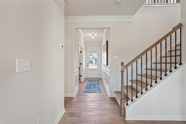 foyer featuring stairway, crown molding, and wood finished floors
