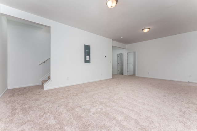 empty room with electric panel, stairway, baseboards, and carpet