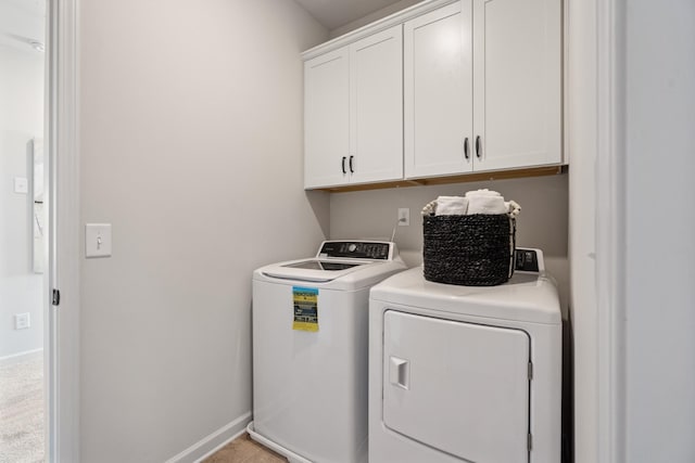 washroom with cabinet space, washer and dryer, and baseboards