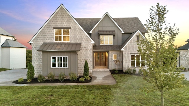 view of front of house with a standing seam roof, a front yard, board and batten siding, and roof with shingles