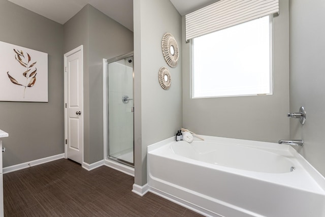 bathroom with a shower stall, a garden tub, and baseboards