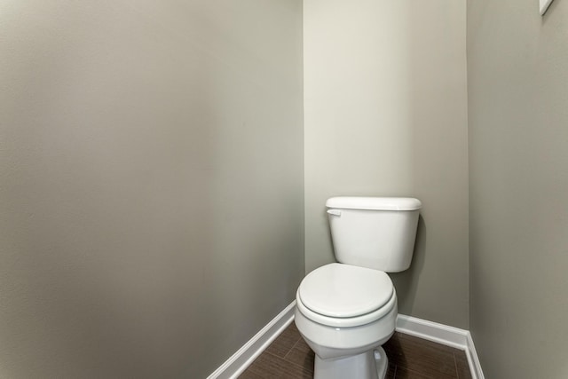 bathroom with toilet, wood finished floors, and baseboards