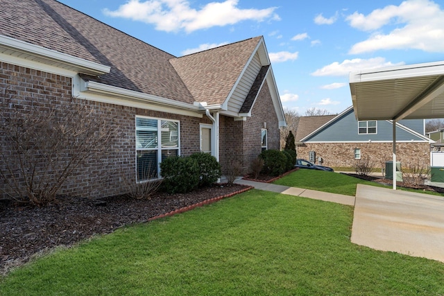 view of side of property featuring brick siding, a yard, and roof with shingles