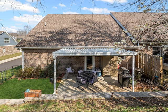 rear view of house with a yard, brick siding, a fenced backyard, and a patio area