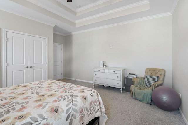 bedroom featuring baseboards, a tray ceiling, ornamental molding, carpet flooring, and a closet