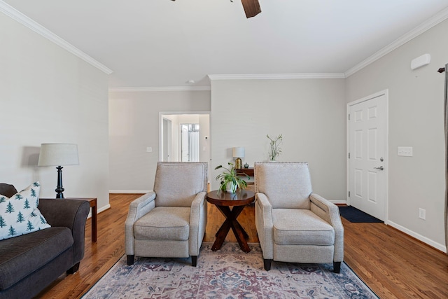 living area with ceiling fan, baseboards, wood finished floors, and ornamental molding