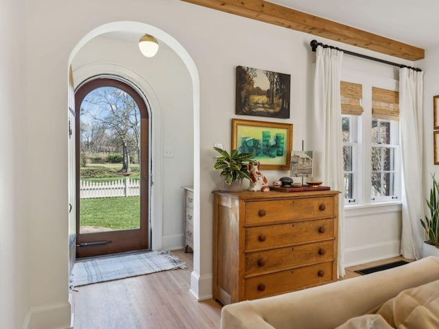 entryway featuring arched walkways, visible vents, baseboards, and wood finished floors