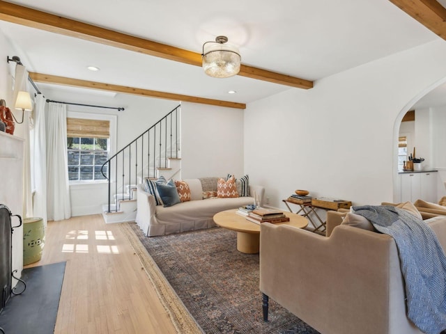 living room with wood finished floors, beam ceiling, recessed lighting, arched walkways, and stairs