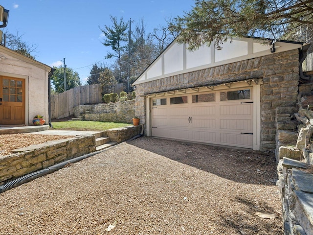 garage featuring driveway and fence