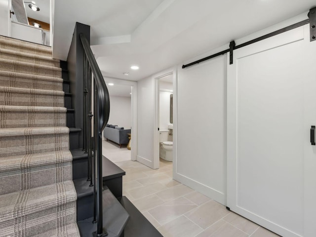 stairway featuring tile patterned flooring, a barn door, recessed lighting, and baseboards