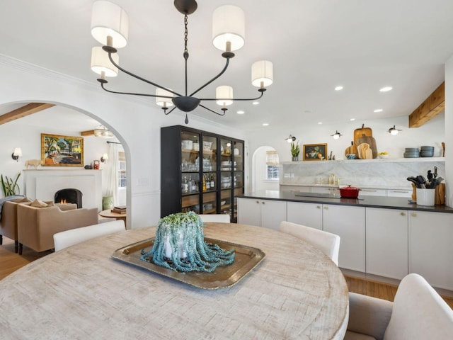 dining room with beam ceiling, recessed lighting, arched walkways, crown molding, and a chandelier