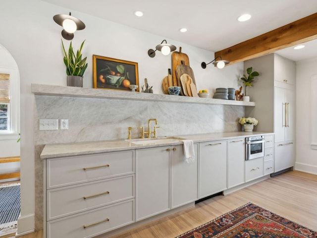 kitchen with a sink, open shelves, light wood-type flooring, and stainless steel oven