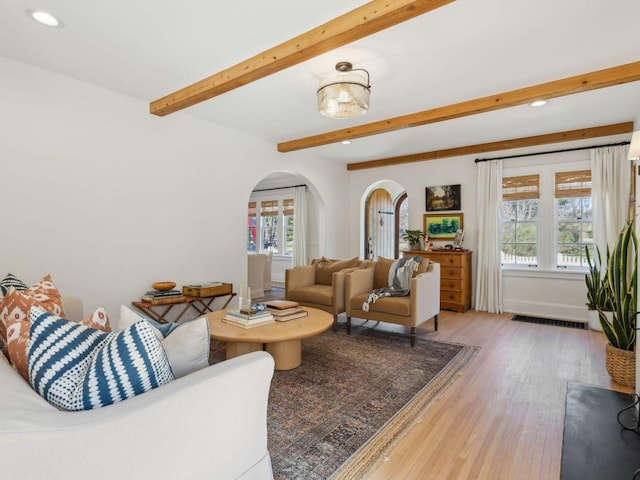 living room with visible vents, beam ceiling, recessed lighting, wood finished floors, and arched walkways