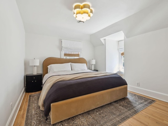 bedroom with baseboards, multiple windows, and wood finished floors