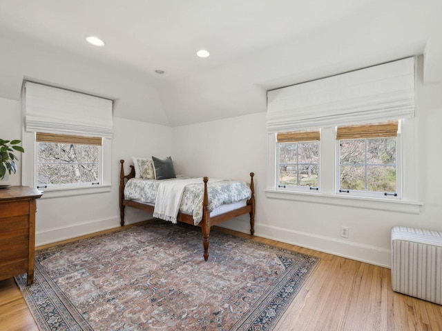 bedroom featuring multiple windows, radiator heating unit, baseboards, and vaulted ceiling