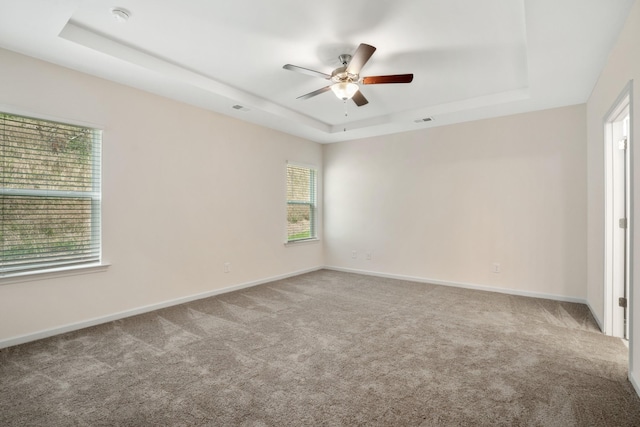 spare room featuring carpet flooring, baseboards, a raised ceiling, and a ceiling fan