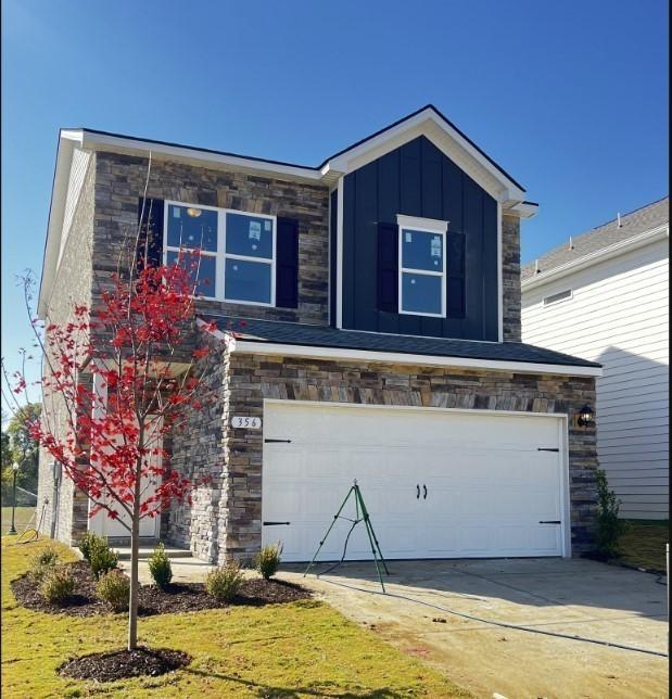 view of front of house with a garage, stone siding, and board and batten siding