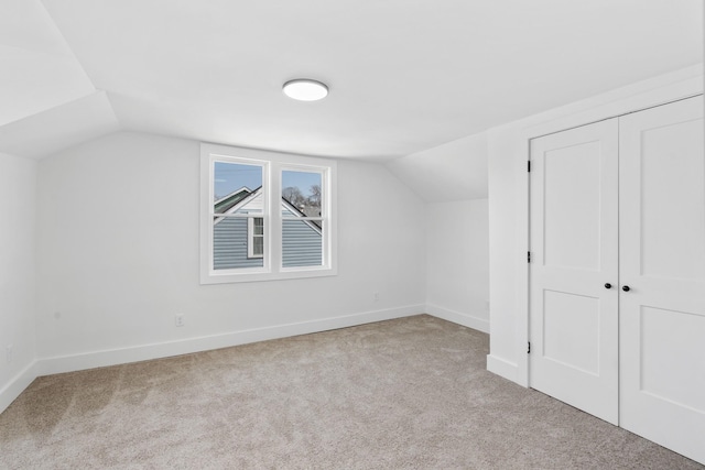 additional living space featuring baseboards, lofted ceiling, and carpet