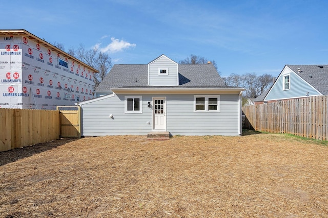 view of front of home with a shingled roof, a fenced backyard, and a front yard