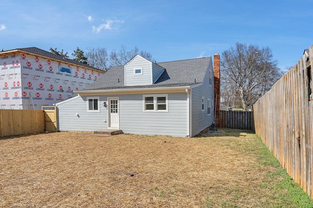 view of front of property with a fenced backyard, a front yard, and a shingled roof