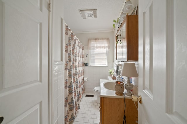 bathroom with tile patterned flooring, tile walls, toilet, vanity, and a textured ceiling