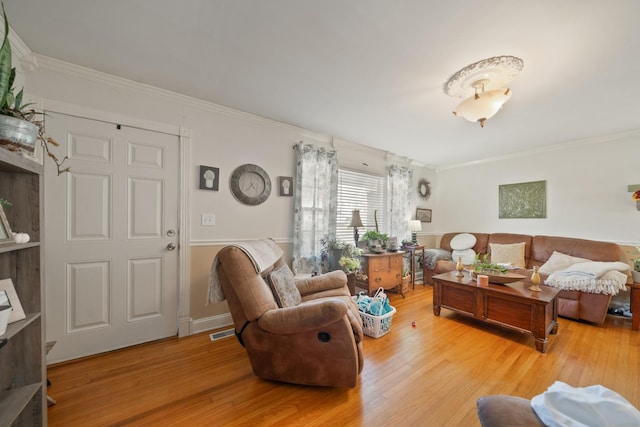 living area featuring light wood-style floors, visible vents, and ornamental molding