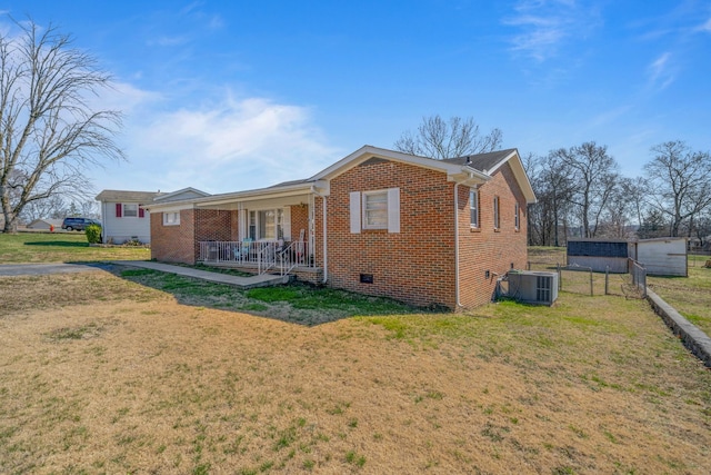 view of front of home with a front lawn, central air condition unit, brick siding, and covered porch