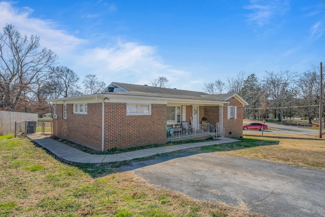 view of front of house with a front lawn, fence, brick siding, and covered porch