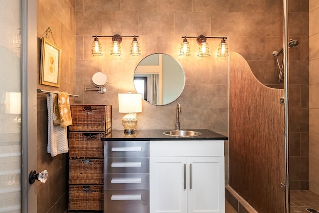 full bath with tile walls, a stall shower, and vanity