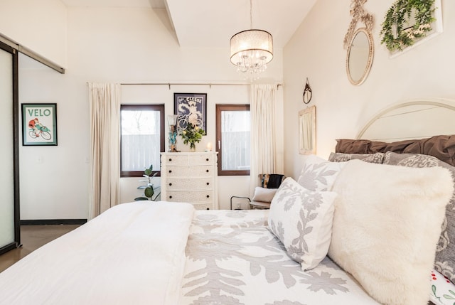 bedroom featuring wood finished floors, lofted ceiling, and a chandelier