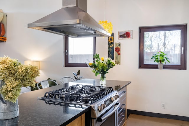 kitchen with island exhaust hood, baseboards, and stainless steel gas range oven