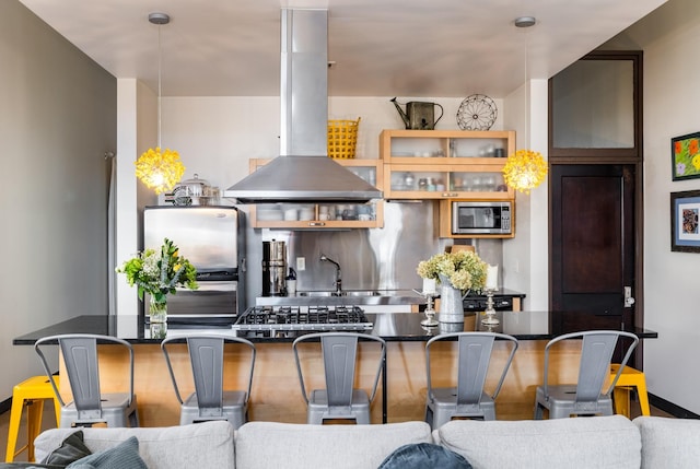 kitchen with open floor plan, island exhaust hood, stainless steel appliances, and a kitchen breakfast bar