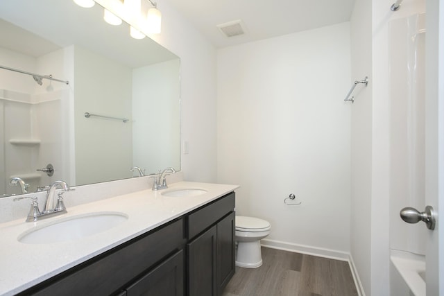 bathroom with toilet, wood finished floors, visible vents, and a sink