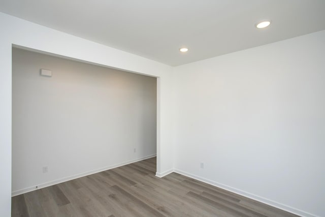 spare room featuring recessed lighting, baseboards, and wood finished floors