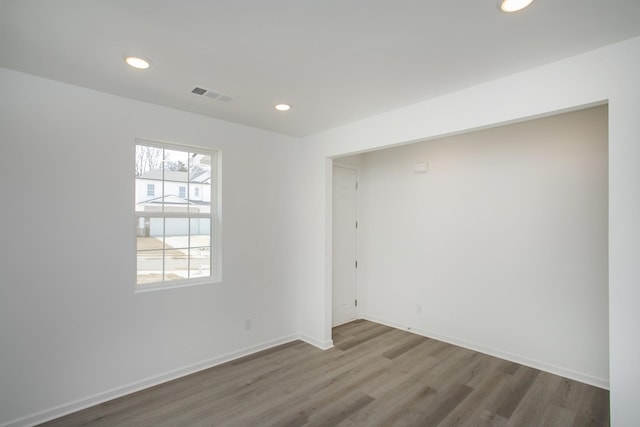 empty room featuring recessed lighting, wood finished floors, visible vents, and baseboards