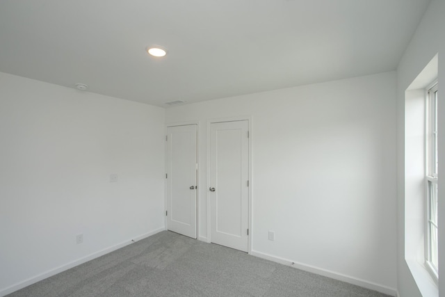 spare room with baseboards and light carpet