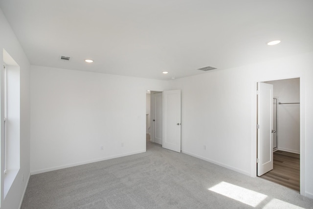 carpeted empty room featuring recessed lighting, visible vents, and baseboards